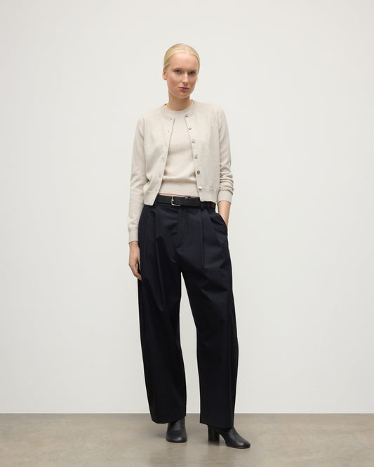 MODEL WEARING JOHNSTONS OF ELGIN WOMENS IRIS CLASSIC CREW CARDIGAN NATURAL 100% CASHMERE WITH NAVY TROUSERS AND BLACK BOOTS KAP05704HA0402