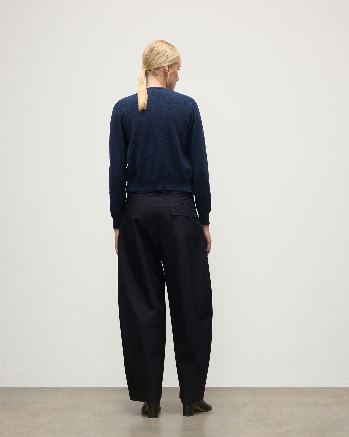 MODEL WEARING JOHNSTONS OF ELGIN WOMENS IRIS CLASSIC CREW CARDIGAN NAVY 100% CASHMERE, OVER A MATCHING SLEEVELESS TANK WITH NAVY TROUSERS, BLANK BOOTS KAP05704HD7350