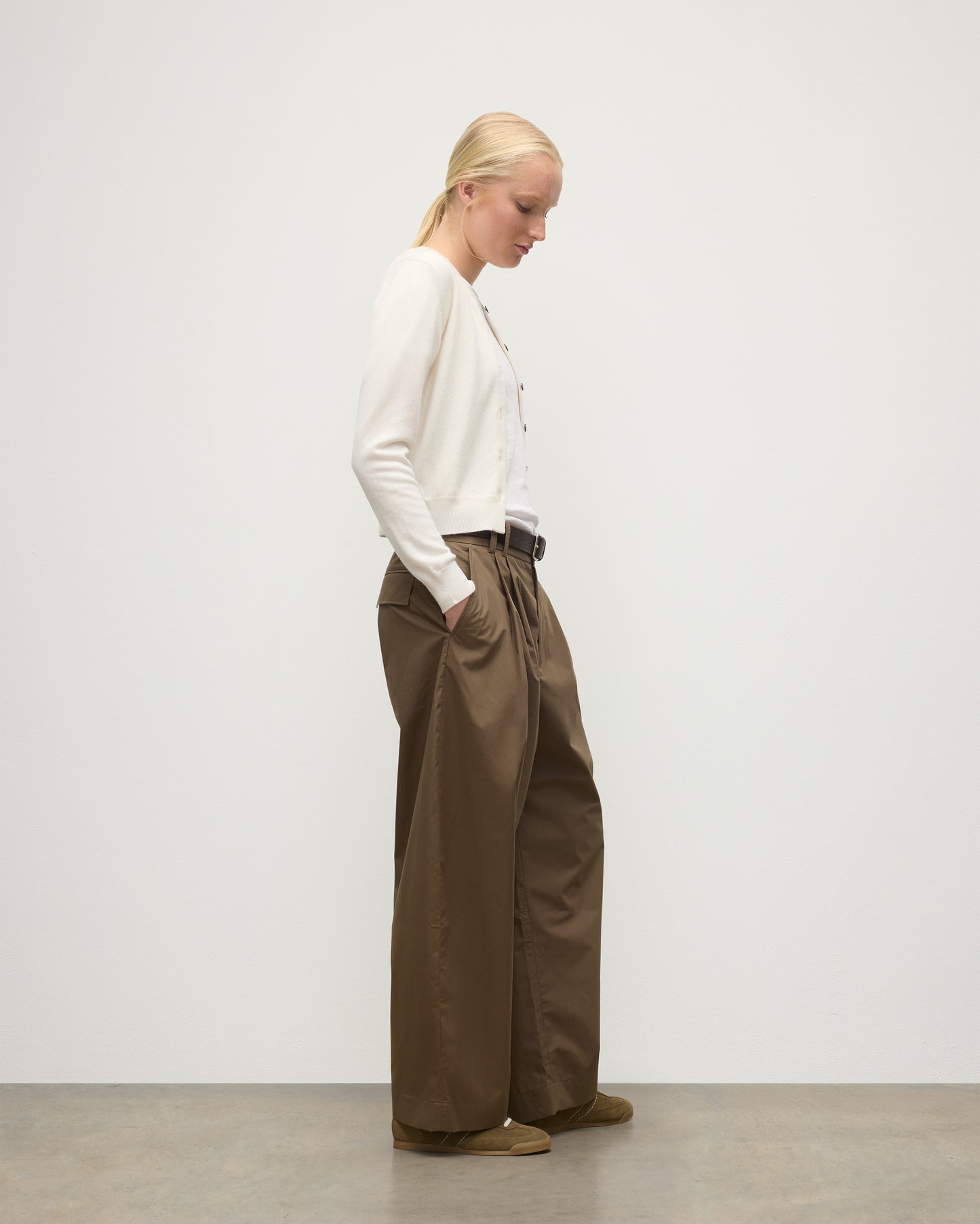 MODEL WEARING JOHNSTONS OF ELGIN WOMENS IRIS CLASSIC CREW CARDIGAN WHITE 100% CASHMERE OVER A WHITE T-SHIRT, WITH BROWN WIDE LEG TROUSERS KAP05704SA0606