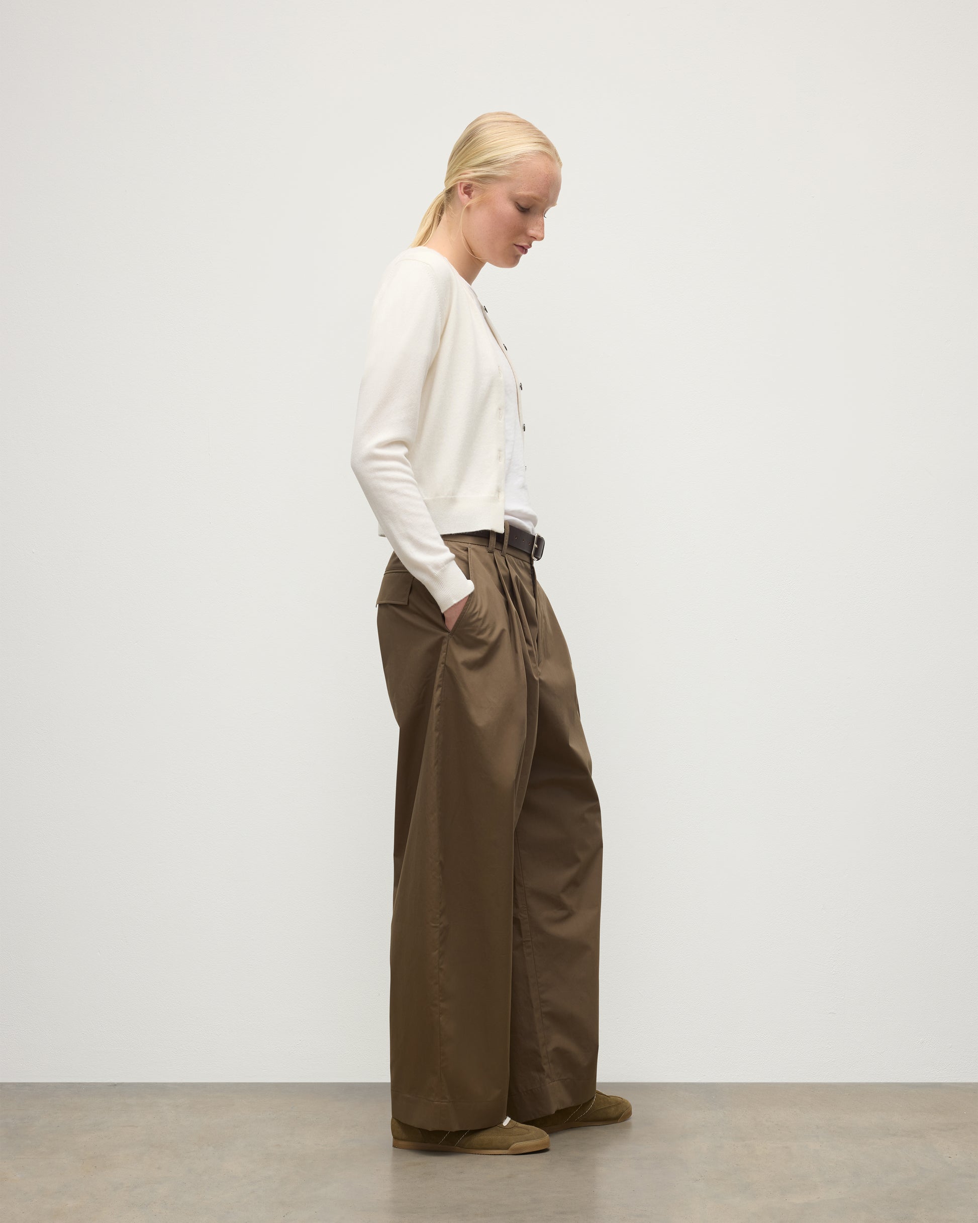 MODEL WEARING JOHNSTONS OF ELGIN WOMENS IRIS CLASSIC CREW CARDIGAN WHITE 100% CASHMERE OVER A WHITE T-SHIRT, WITH BROWN WIDE LEG TROUSERS KAP05704SA0606