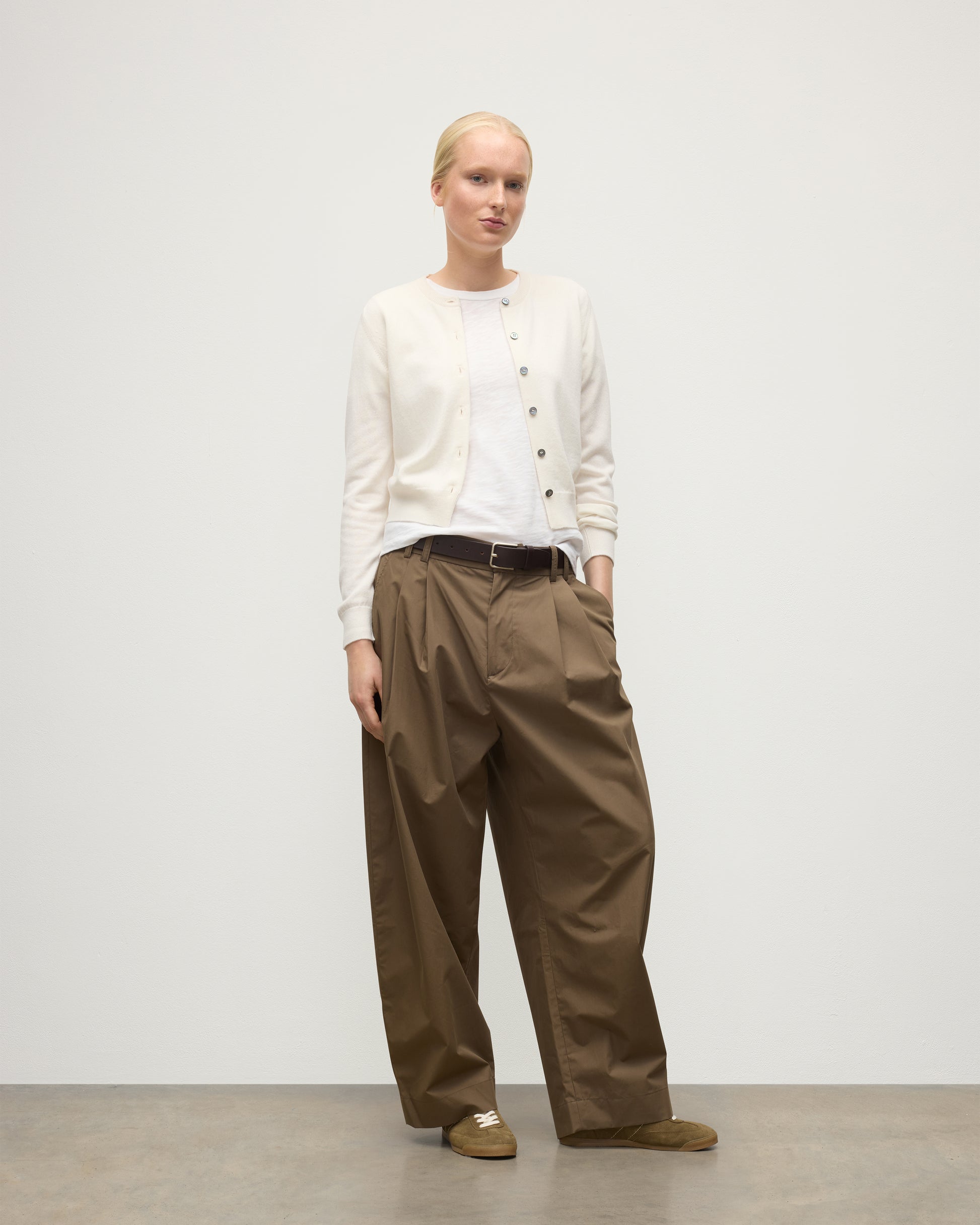 MODEL WEARING JOHNSTONS OF ELGIN WOMENS IRIS CLASSIC CREW CARDIGAN WHITE 100% CASHMERE OVER A WHITE T-SHIRT, WITH BROWN WIDE LEG TROUSERS KAP05704SA0606