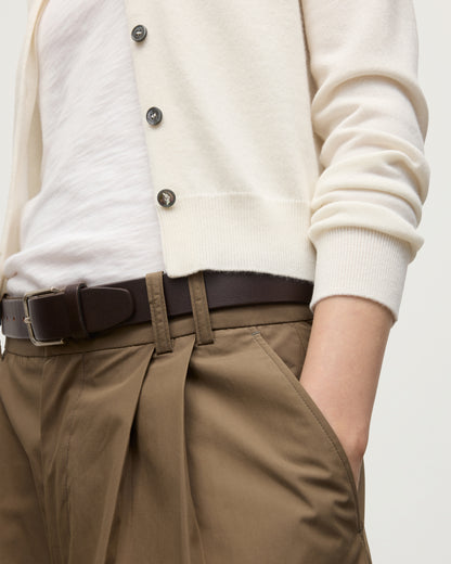 MODEL WEARING JOHNSTONS OF ELGIN WOMENS IRIS CLASSIC CREW CARDIGAN WHITE 100% CASHMERE OVER A WHITE T-SHIRT, WITH BELTED BROWN WIDE LEG TROUSERS KAP05704SA0606