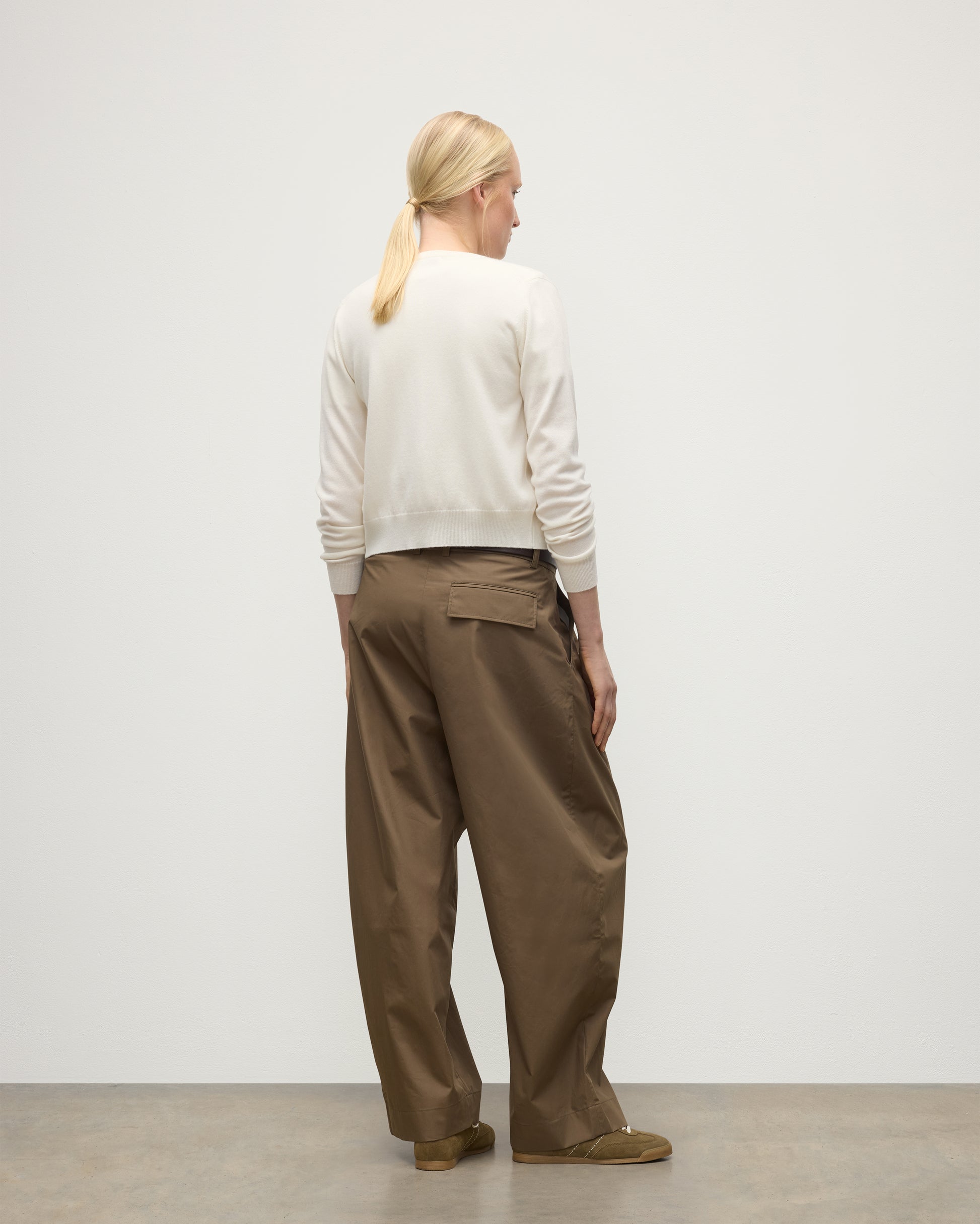 MODEL WEARING JOHNSTONS OF ELGIN WOMENS IRIS CLASSIC CREW CARDIGAN WHITE 100% CASHMERE OVER A WHITE T-SHIRT, WITH BROWN WIDE LEG TROUSERS KAP05704SA0606