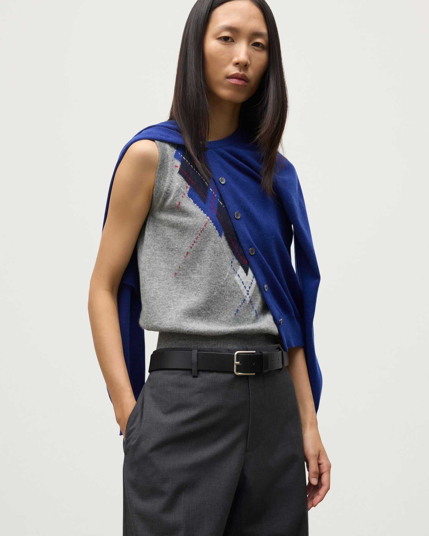 MODEL WEARING JOHNSTONS OF ELGIN WOMENS IRIS CLASSIC CREW CARDIGAN BLUE 100% CASHMERE OVER LE JABOT CASHMERE TANK WITH GREY TROUSERS AND BLACK BOOTS KAP05704SD5326