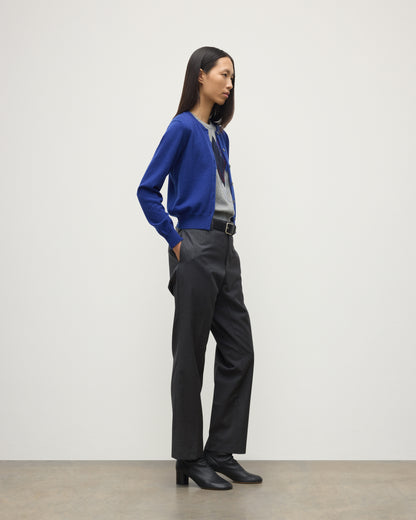 MODEL WEARING JOHNSTONS OF ELGIN WOMENS IRIS CLASSIC CREW CARDIGAN BLUE 100% CASHMERE OVER LE JABOT CASHMERE TANK WITH GREY TROUSERS AND BLACK BOOTS KAP05704SD5326