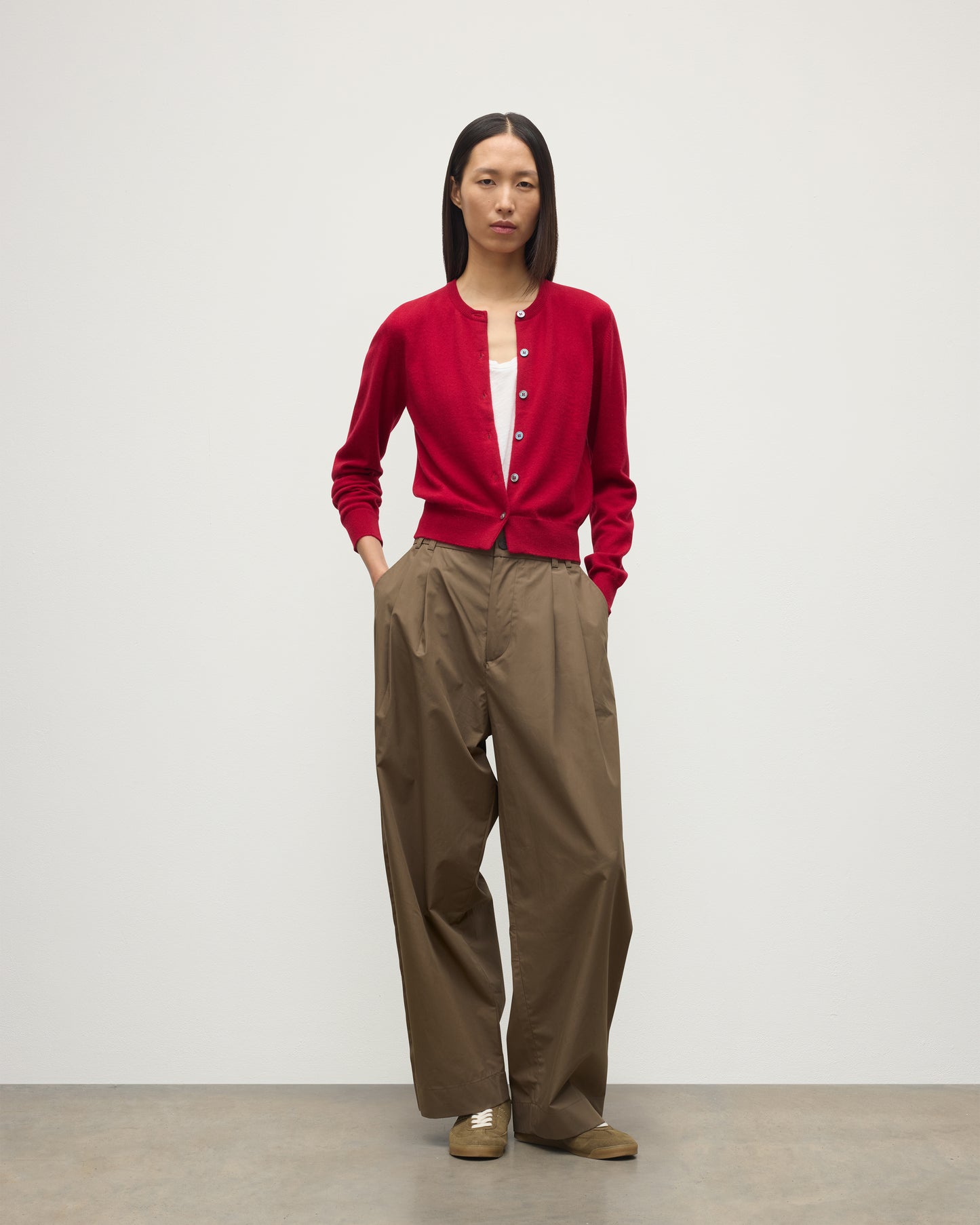 MODEL WEARS JOHNSTONS OF ELGIN WOMENS IRIS CLASSIC CREW CARDIGAN RED 100% CASHMERE OVER A WHITE VEST WITH BROWN TROUSERS AND TRAINERS  KAP05704SE5325