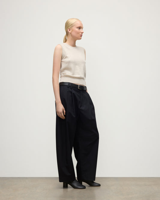 MODEL WEARS JOHNSTONS OF ELGIN WOMENS IRIS CLASSIC SLEEVELESS CREW NATURAL 100% CASHMERE WITH NAVY TROUSERS AND BLACK BOOTS  KAP05705HA0402