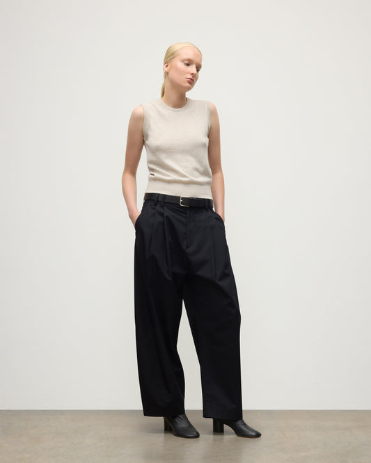 MODEL WEARS JOHNSTONS OF ELGIN WOMENS IRIS CLASSIC SLEEVELESS CREW NATURAL 100% CASHMERE WITH NAVY TROUSERS AND BLACK BOOTS  KAP05705HA0402