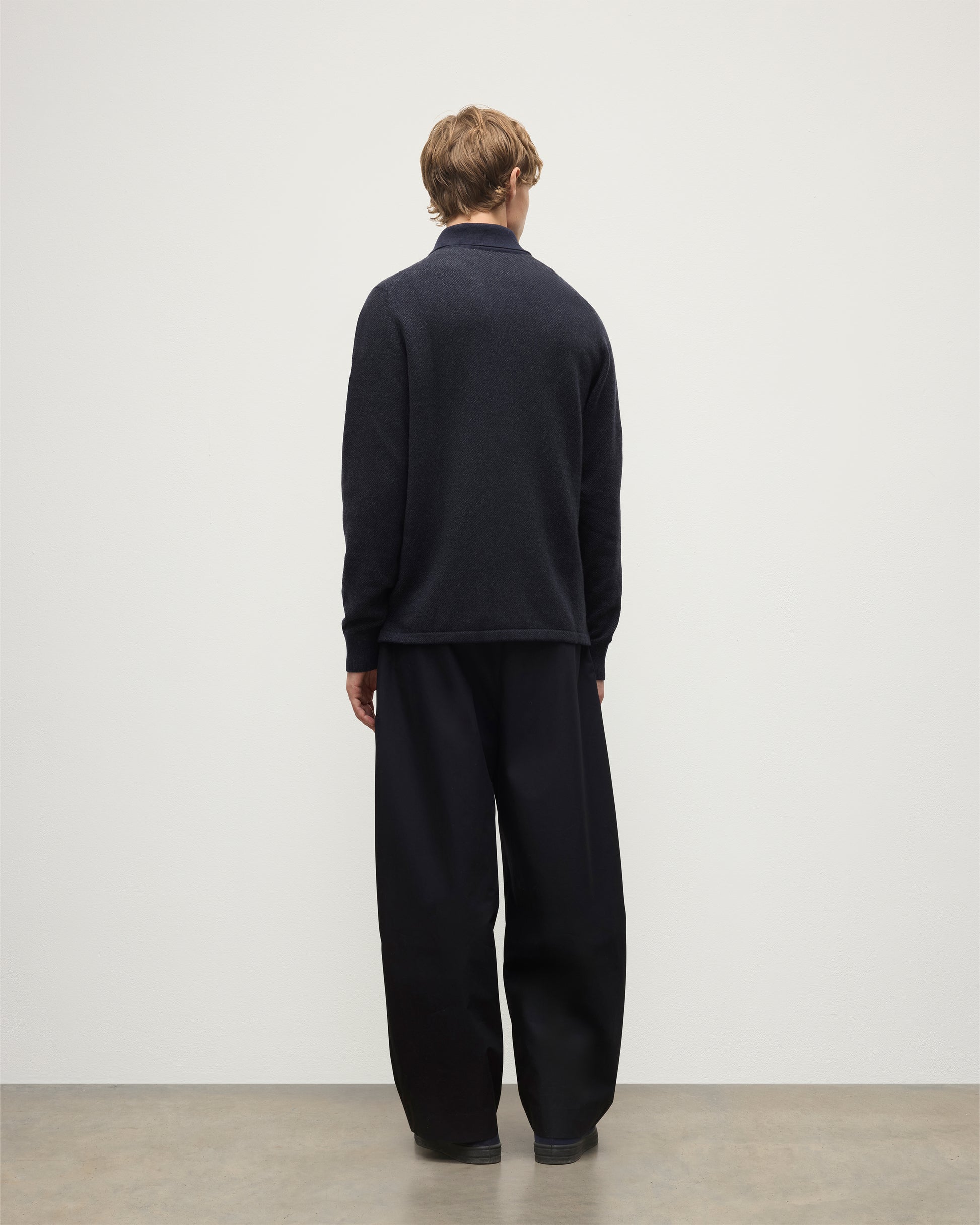 MODEL WEARS JOHNSTONS OF ELGIN MENS TWEEL RUGBY SHIRT NAVY & DARK GREY 100% CASHMERE  OVER A WHITE T-SHIRT WITH GREY TROUSERS KAP05727Q25937