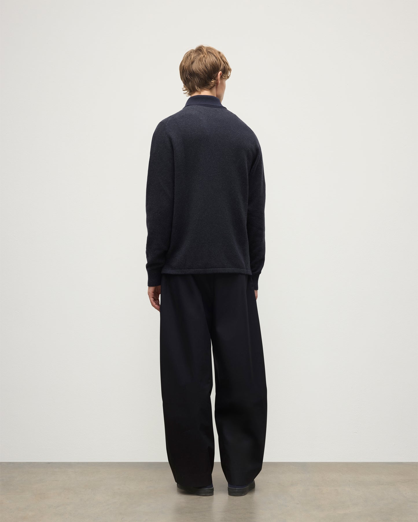 MODEL WEARS JOHNSTONS OF ELGIN MENS TWEEL RUGBY SHIRT NAVY & DARK GREY 100% CASHMERE  OVER A WHITE T-SHIRT WITH GREY TROUSERS KAP05727Q25937