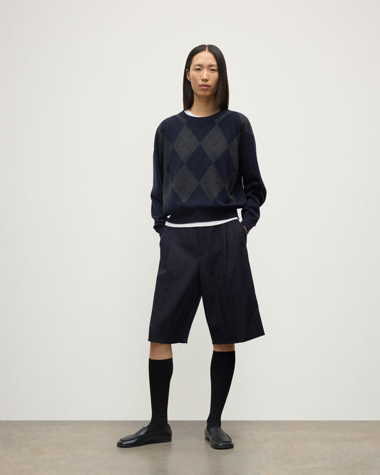 MODEL WEARS JOHNSTONS OF ELGIN WOMENS CLAN SLOUCH CREW NAVY 100% CASHMERE OVER A WHITE TEE, WITH NAVY LONG SHORTS, CASHMERE SOCKS AND LOAFERS KAP05732JU1606