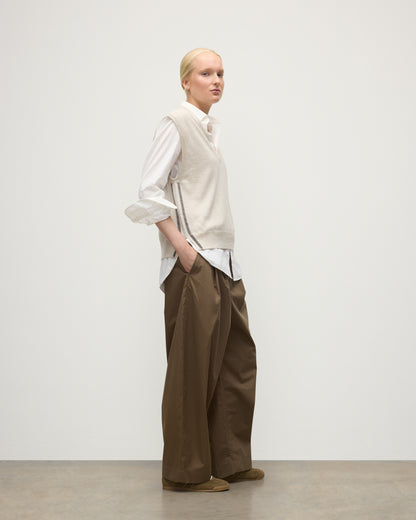 MODEL WEARS JOHNSTONS OF ELGIN WOMENS TILDA SLEEVELESS VEE NATURAL 100% CASHMERE OVER A WHITE SHIRT, WITH BROWN TROUSERS KAP05767Q25969