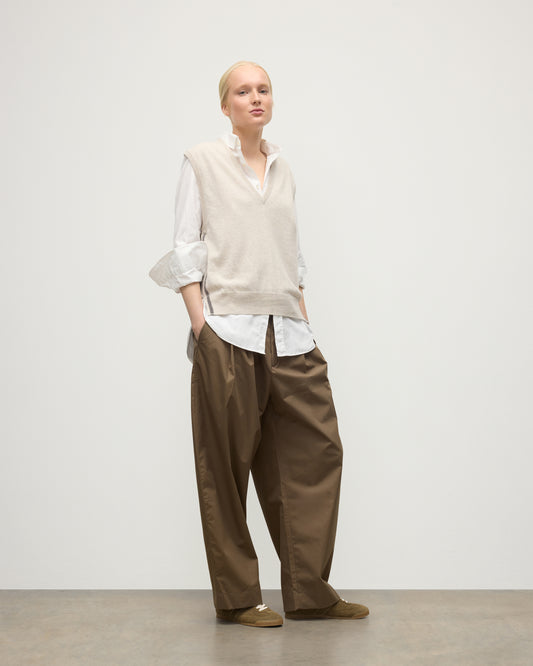 MODEL WEARS JOHNSTONS OF ELGIN WOMENS TILDA SLEEVELESS VEE NATURAL 100% CASHMERE OVER A WHITE SHIRT, WITH BROWN TROUSERS KAP05767Q25969