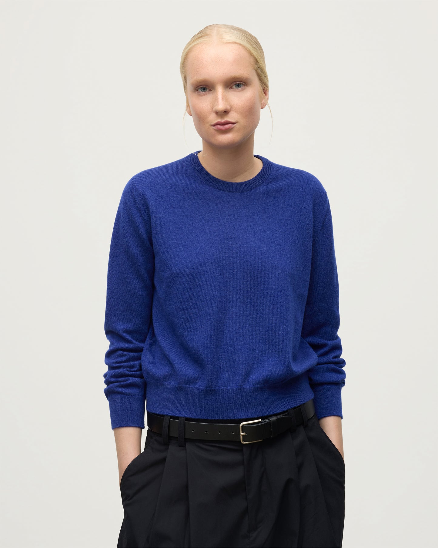 MODEL WEARS JOHNSTONS OF ELGIN WOMENS LUNAN CLASSIC CREW SWEATER BLUE  WITH BELTED BLACK TROUSERS KAP05784SD5326