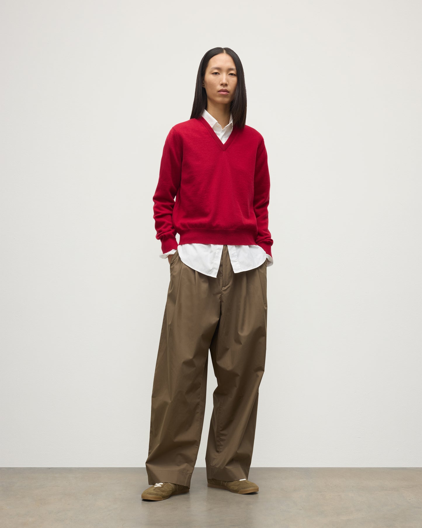 MODEL WEARING JOHNSTONS OF ELGIN WOMENS LUNAN CLASSIC VEE SWEATER RED 100% CASHMERE OVER WHITE SHIRT WITH BROWN TROUSERS KAP05807SE5325