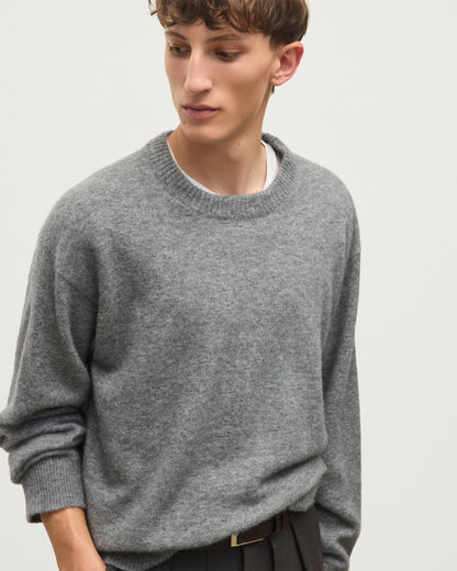 A man wearing a heather gray crewneck sweater over a white undershirt, paired with dark trousers and a brown belt, photographed against a plain light gray background. JOHNSTONS OF ELGIN REUBEN CREW CASHMERE CREW NECK SWEATER - 2 PLY GREY 100% CASHMERE KAP06051SA7216