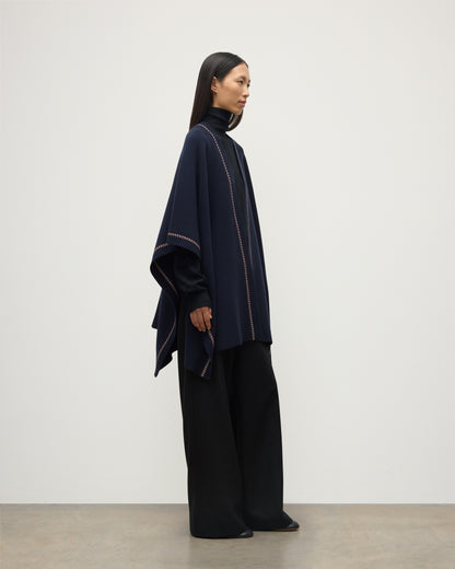 MODEL WEARS JOHNSTONS OF ELGIN WOMENS HAWK PONCHO NAVY 100% CASHMERE OVER NAVY ROLL NECK SWEATER AND NAVY TROUSERS KAU05769Q25973O/S