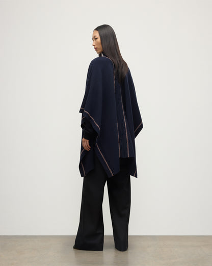 MODEL WEARS JOHNSTONS OF ELGIN WOMENS HAWK PONCHO NAVY 100% CASHMERE OVER NAVY ROLL NECK SWEATER AND NAVY TROUSERS KAU05769Q25973O/S