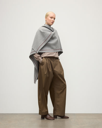MODEL WEARS JOHNSTONS OF ELGIN WOMENS HAWK PONCHO LIGHT GREY 100% CASHMERE OVER A NATURAL CASHMERE SWEATER AND BROWN TROUSERS KAU05769Q25974O/S