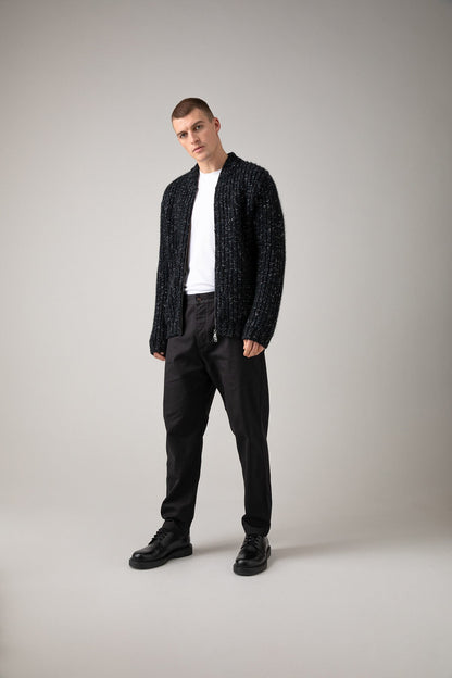 Johnstons of Elgin’s Men's Cashmere Blend Ribbed Baseball Cardigan in Black on model wearing black trousers on a grey background KBB00934Q23636