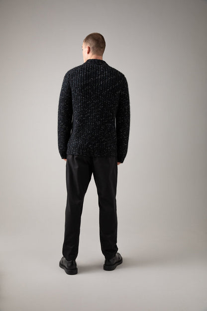 Johnstons of Elgin’s Men's Cashmere Blend Ribbed Baseball Cardigan in Black on model wearing black trousers on a grey background KBB00934Q23636