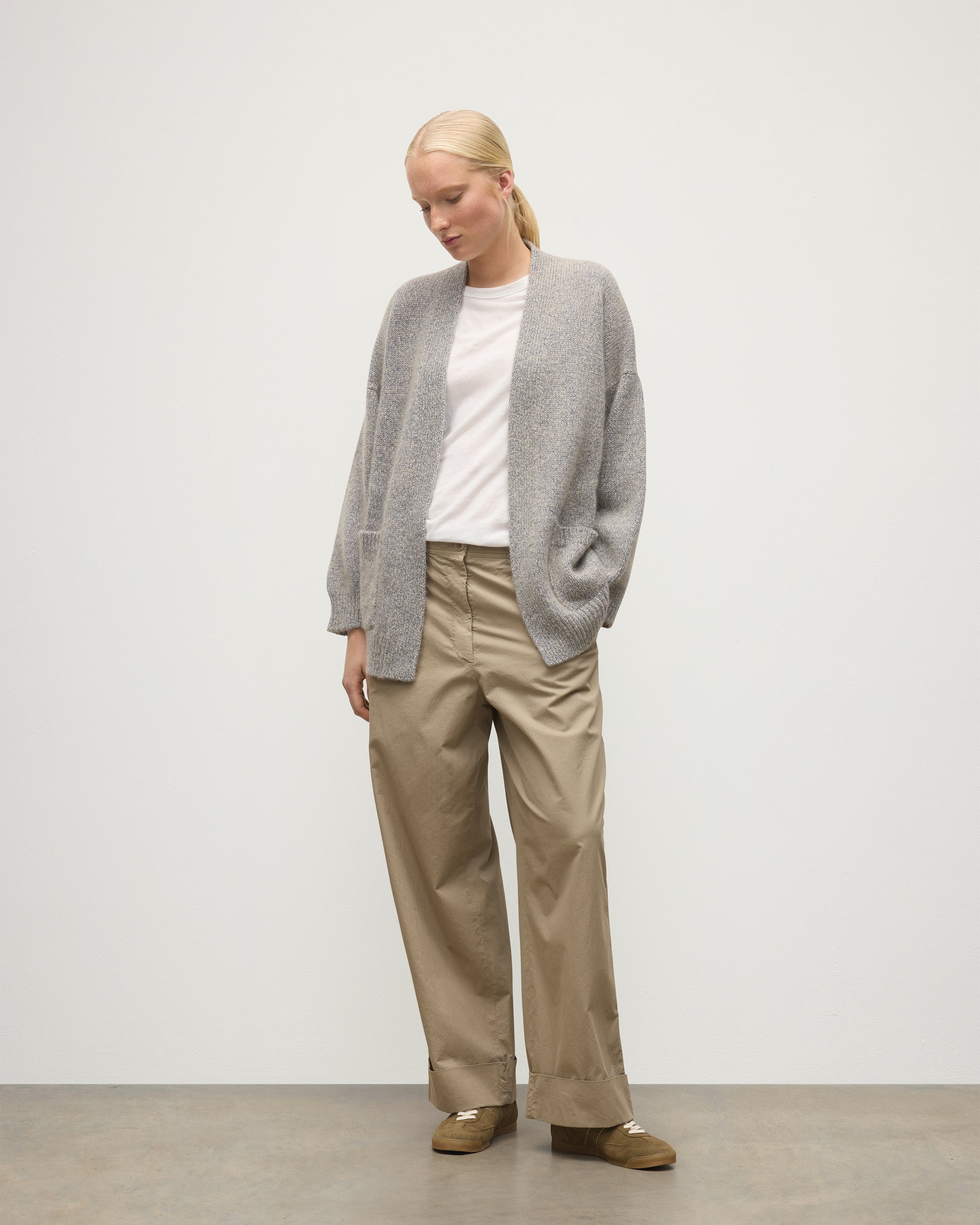 MODEL WEARS JOHNSTONS OF ELGIN WOMENS BAY SLOUCH CARDIGAN BLUE 78% CASHMERE 22% COTTON OVER A WHITE T-SHIRT WITH BROWN TROUSERS KBB01069HD4499