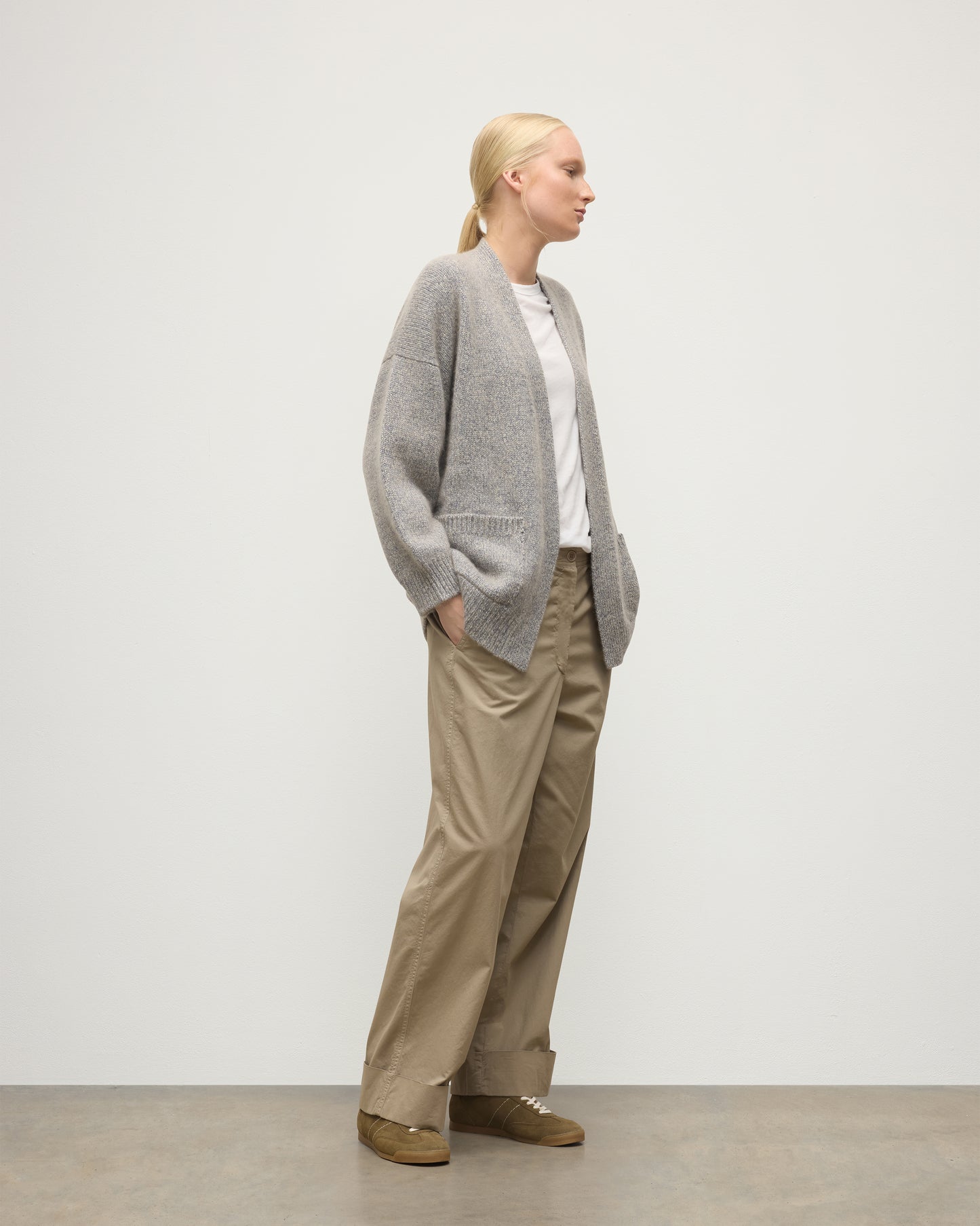 MODEL WEARS JOHNSTONS OF ELGIN WOMENS BAY SLOUCH CARDIGAN BLUE 78% CASHMERE 22% COTTON OVER A WHITE T-SHIRT WITH BROWN TROUSERS KBB01069HD4499