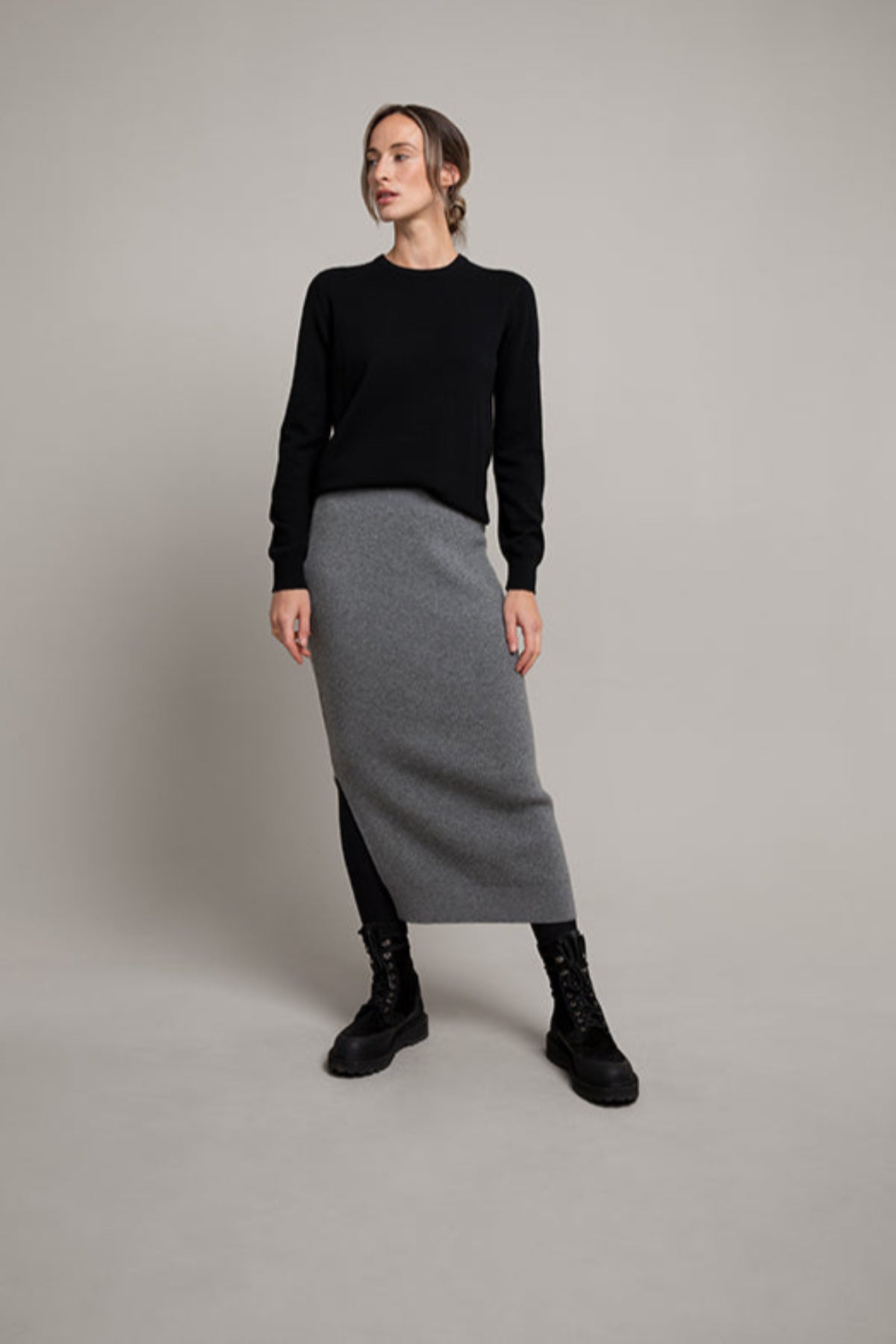 Woman wearing a black sweater and gray skirt on a plain background KBP00923HA5931