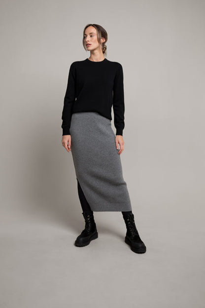 Woman wearing a black sweater and gray skirt on a plain background KBP00923HA5931