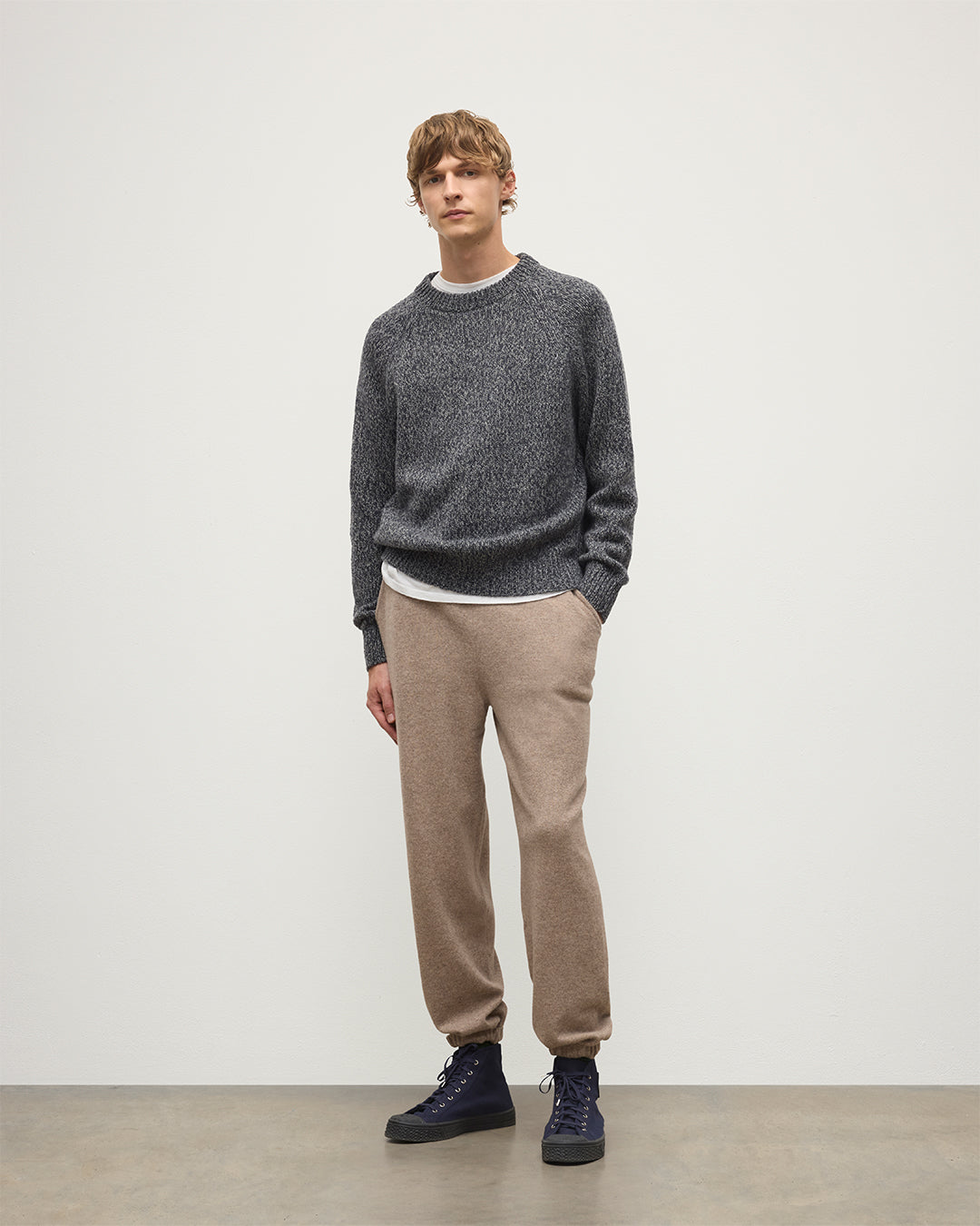 MODEL WEARS JOHNSTONS OF ELGIN MENS KIRK SWEATPANTS LIGHT BROWN 97% CASHMERE 3% POLYESTER WITH A  WHITE T-SHIRT AND NAVY FYFE CASHMERE SWEATER KBP00948HB4334