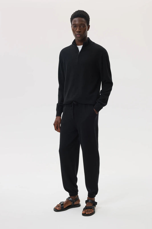 model wearing Johnstons of Elgin SS25 Men's Knitwear Black Tapered Cashmere Joggers worn with matching zip neck sweater over a white t-shirt  KBP00948SA7099