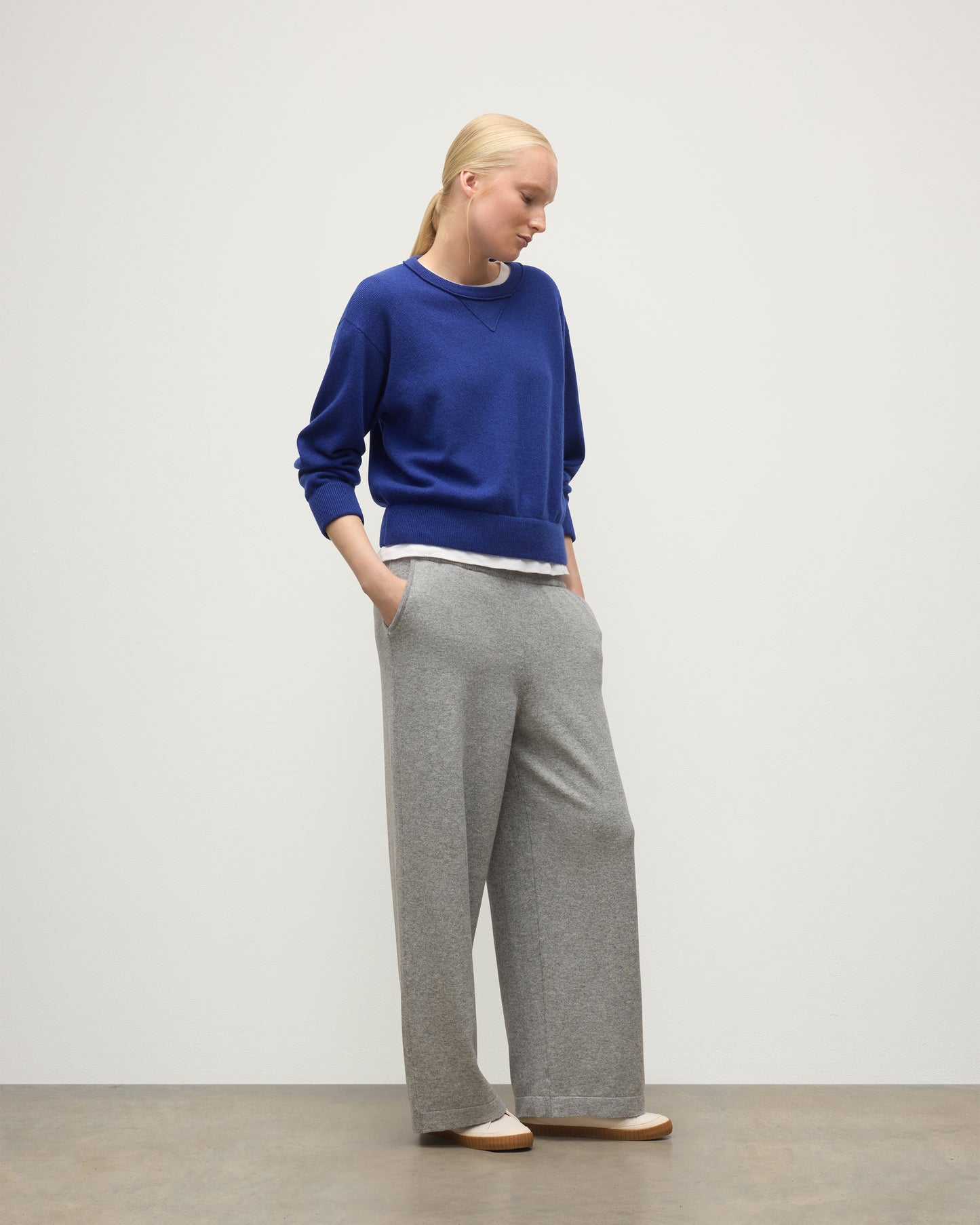MODEL WEARS JOHNSTONS OF ELGIN WOMENS COLL PANTS LIGHT GREY WITH BLUE CASHMERE SWEATER OVER A WHITE T-SHIRT KBP00996HA0308