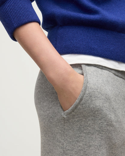 MODEL WEARS JOHNSTONS OF ELGIN WOMENS COLL PANTS LIGHT GREY WITH BLUE CASHMERE SWEATER OVER A WHITE T-SHIRT KBP00996HA0308