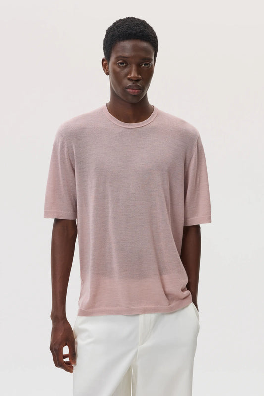 Model wearing Johnstons of Elgin SS25 Men's Knitwear Dusty Rose Superfine Merino T-Shirt with white trousers KDI00663SE5215