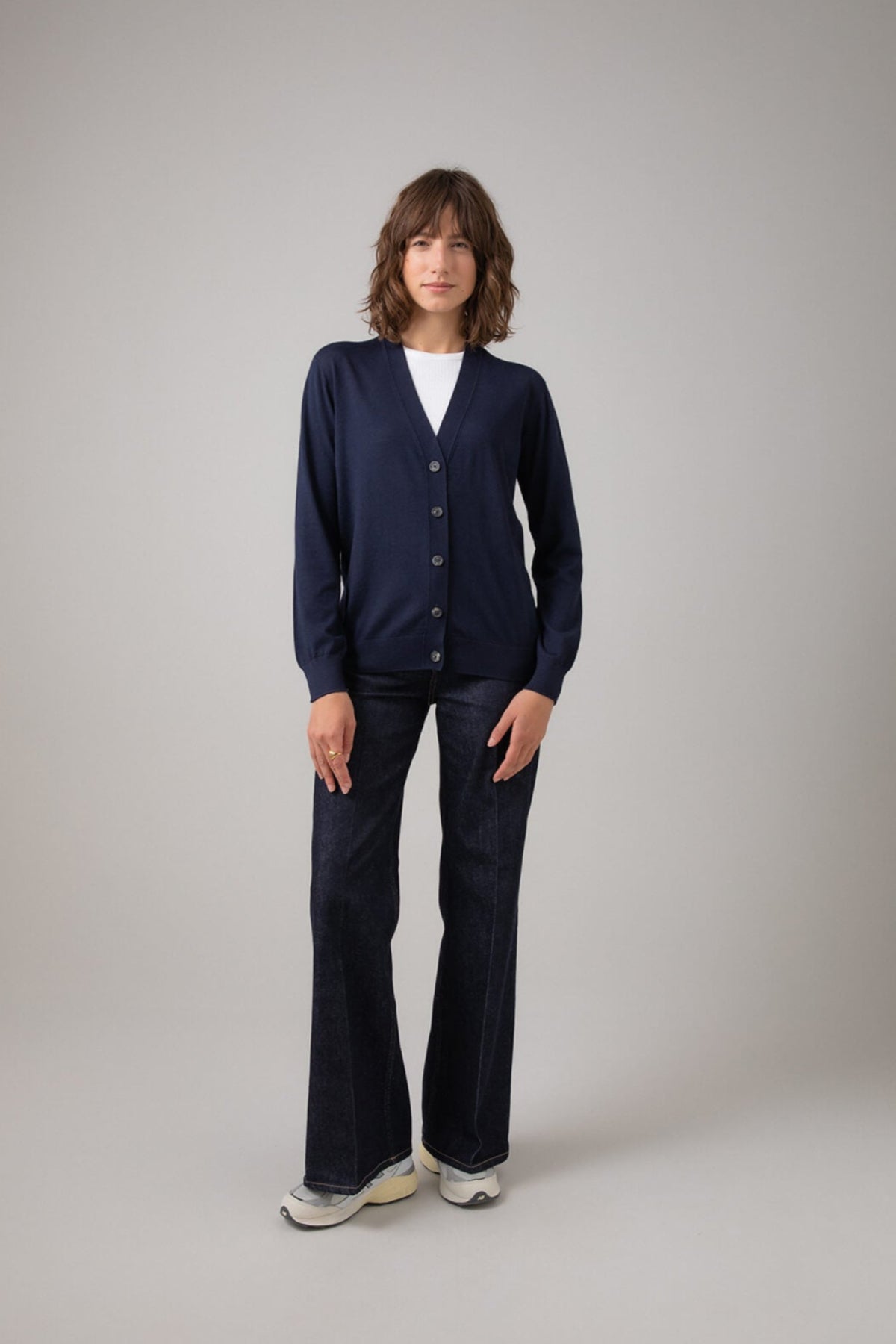 Person wearing a navy cardigan and dark pants on a plain background KDI00684SD7563
