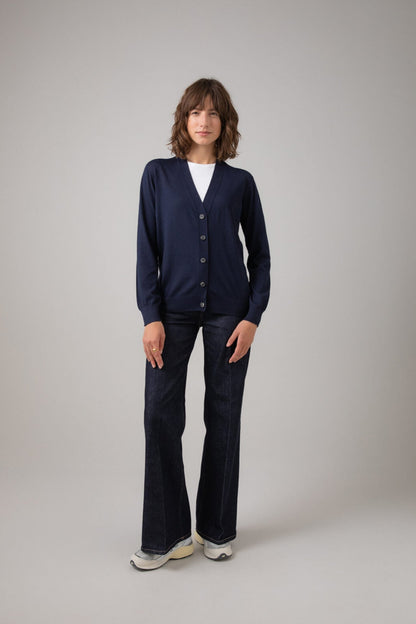 Person wearing a navy cardigan and dark pants on a plain background KDI00684SD7563
