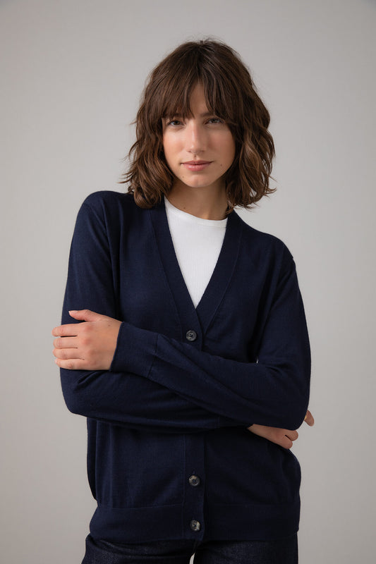 Woman wearing a navy cardigan over a white shirt against a plain background KDI00684SD7563