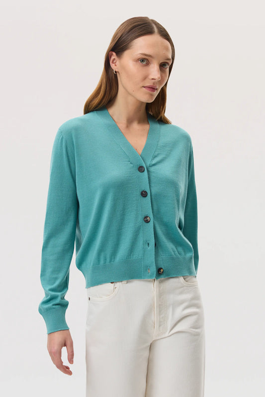 Model wears Johnstons of Elgin SS25 Women's Knitwear Jade Superfine Merino Wool Cardigan with white trousers KDI00686SC4641