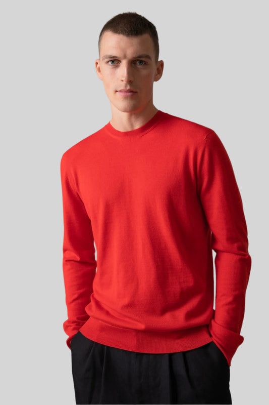 Johnstons of Elgin Men’s Merino Round Neck Jumper in Orkney Red on model wearing black trousers on grey background KDI00702SE4922