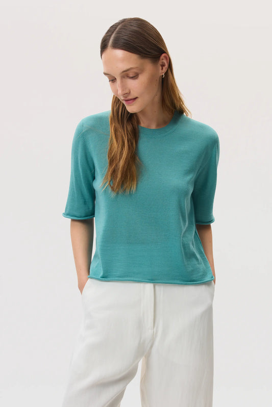 Model wears Johnstons of Elgin SS25 Women's Knitwear Jade Superfine Merino Wool T-Shirt with white jeans KDI00708SC4641