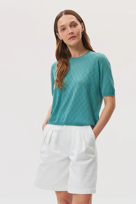 Model wears Johnstons of Elgin SS25 Women's Knitwear Jade Superfine Merino Pointelle Argyle T-Shirt with white shorts KDI00739SC464