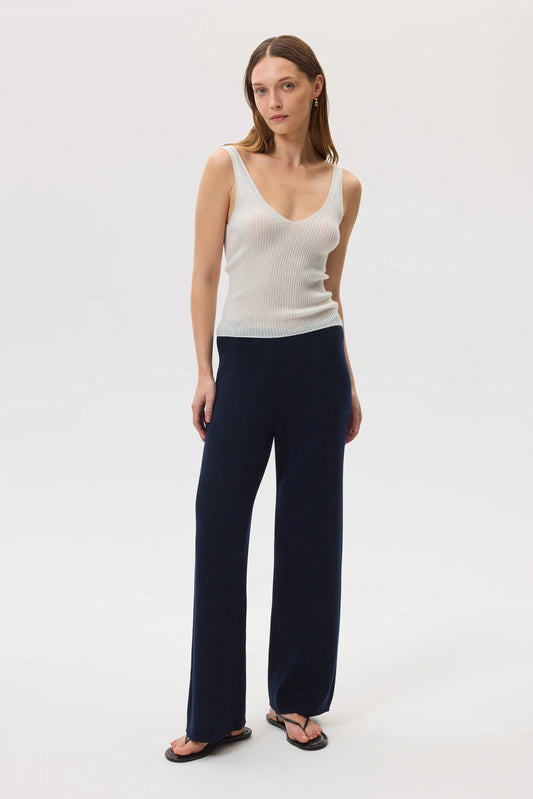 Model wears Johnstons of Elgin SS25 Women's Knitwear Navy Ribbed Merino Wide Leg Trousers with superfine cashmere ribbed vest top in white and black sandals KDP00746SD7645