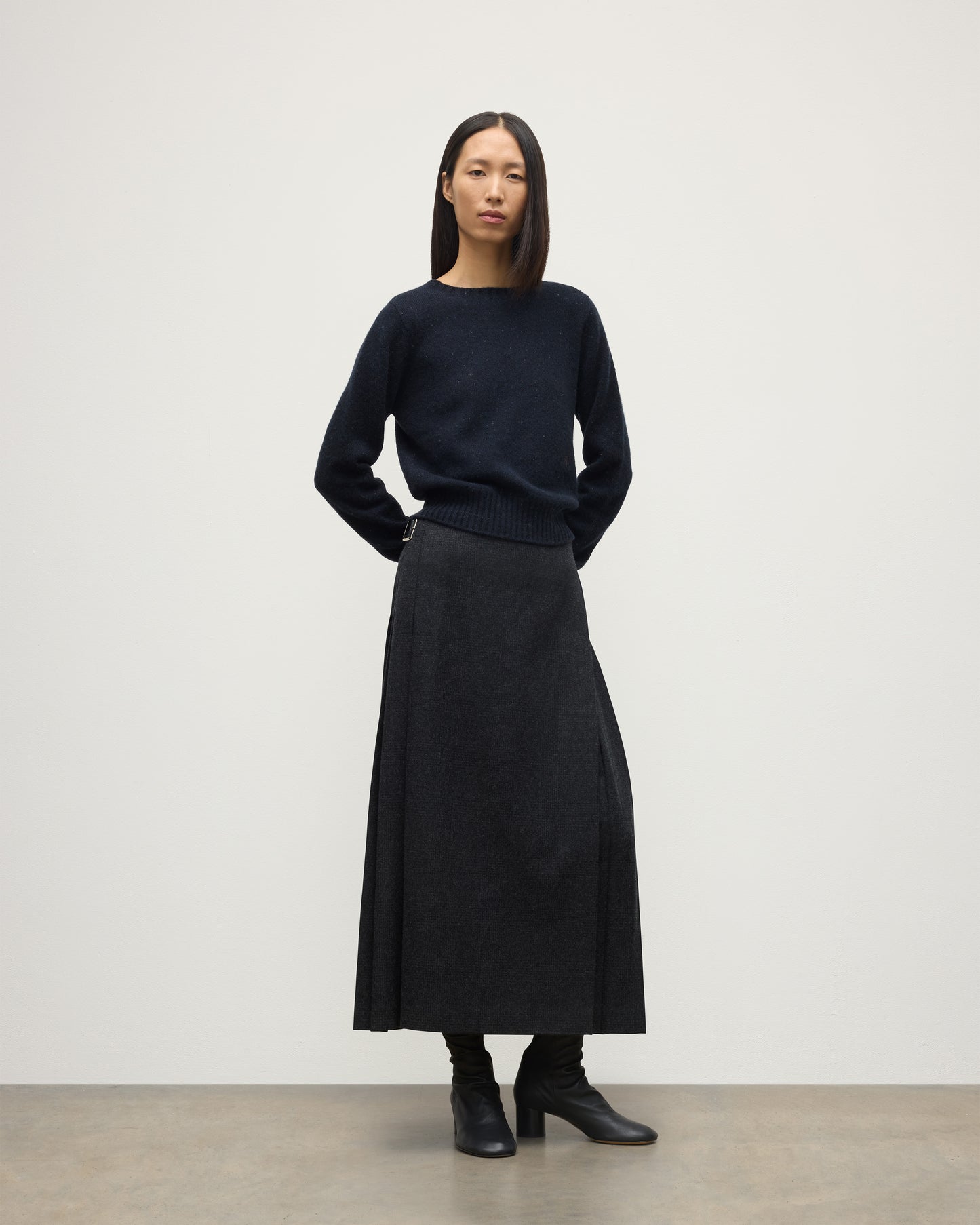 MODEL WEARING LE KILT X JOHNSTONS OF ELGIN LONG CHARCOAL KILT IN WOOL AND CASHMERE, WOR WITH DARK GREY CASHMERE SWEATER WITH BLACK BOOTS TB000844RU7750