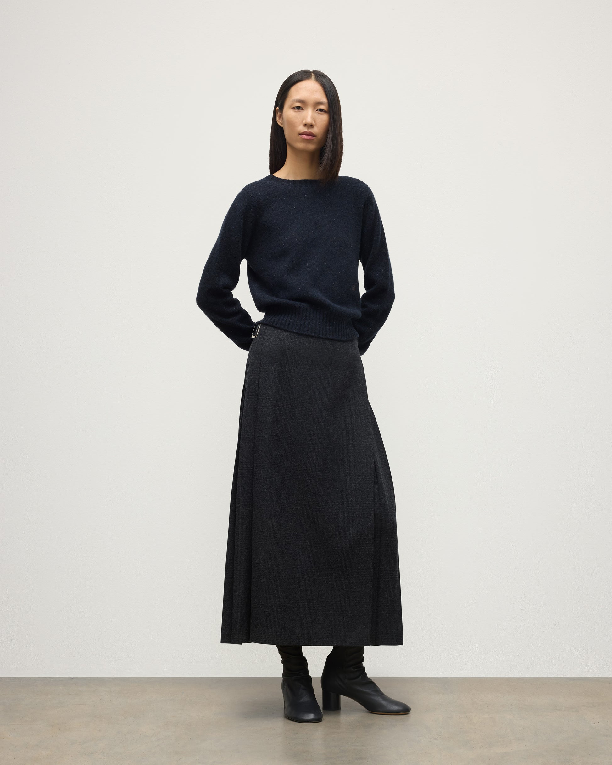 MODEL WEARING LE KILT X JOHNSTONS OF ELGIN LONG CHARCOAL KILT IN WOOL AND CASHMERE, WOR WITH DARK GREY CASHMERE SWEATER WITH BLACK BOOTS TB000844RU7750