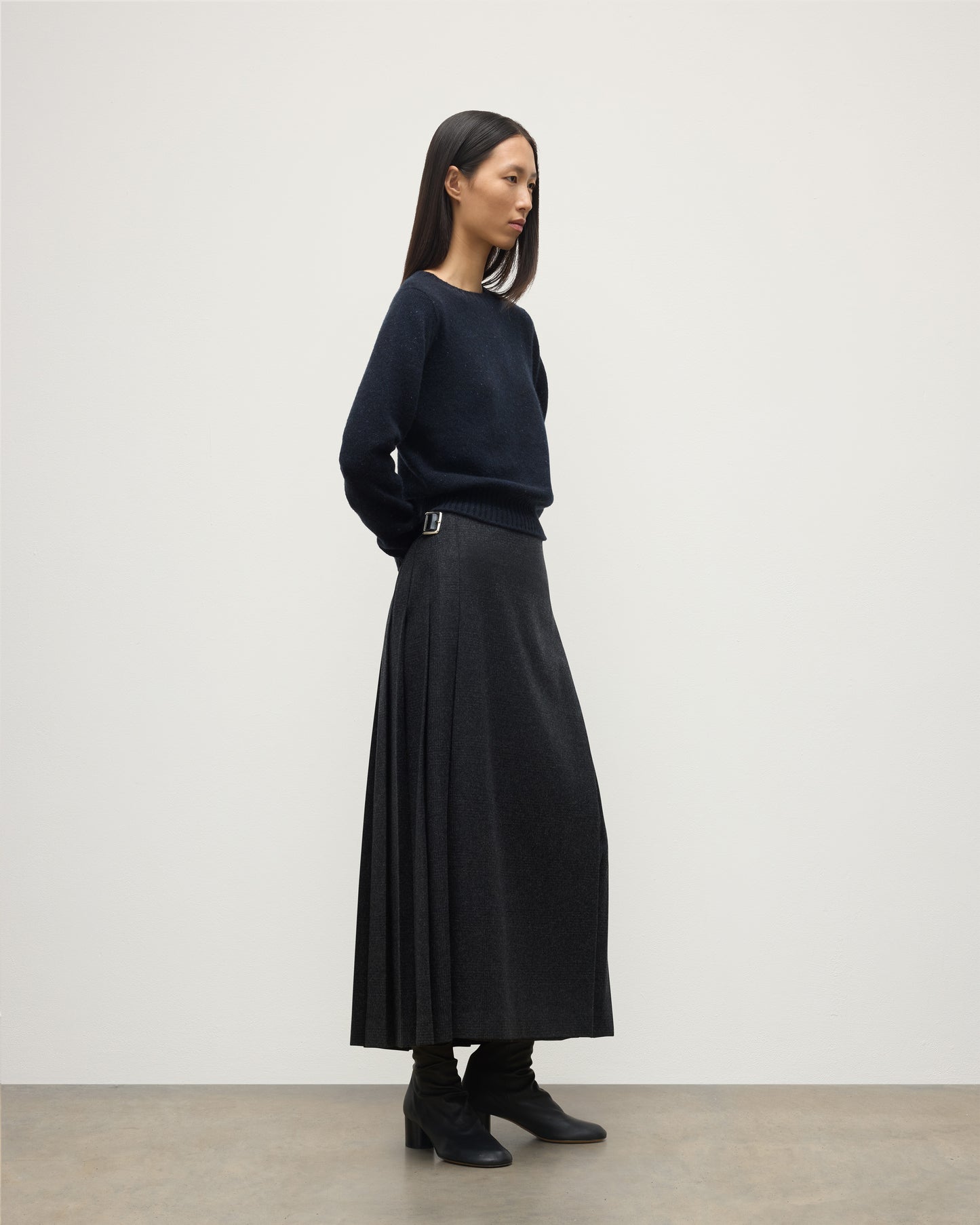 MODEL WEARING LE KILT X JOHNSTONS OF ELGIN LONG CHARCOAL KILT IN WOOL AND CASHMERE, WOR WITH DARK GREY CASHMERE SWEATER WITH BLACK BOOTS TB000844RU7750