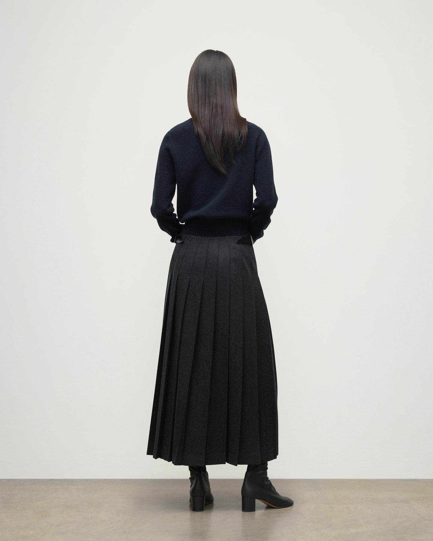 MODEL WEARING LE KILT X JOHNSTONS OF ELGIN LONG CHARCOAL KILT IN WOOL AND CASHMERE, WORN WITH DARK GREY CASHMERE SWEATER WITH BLACK BOOTS TB000844RU7750