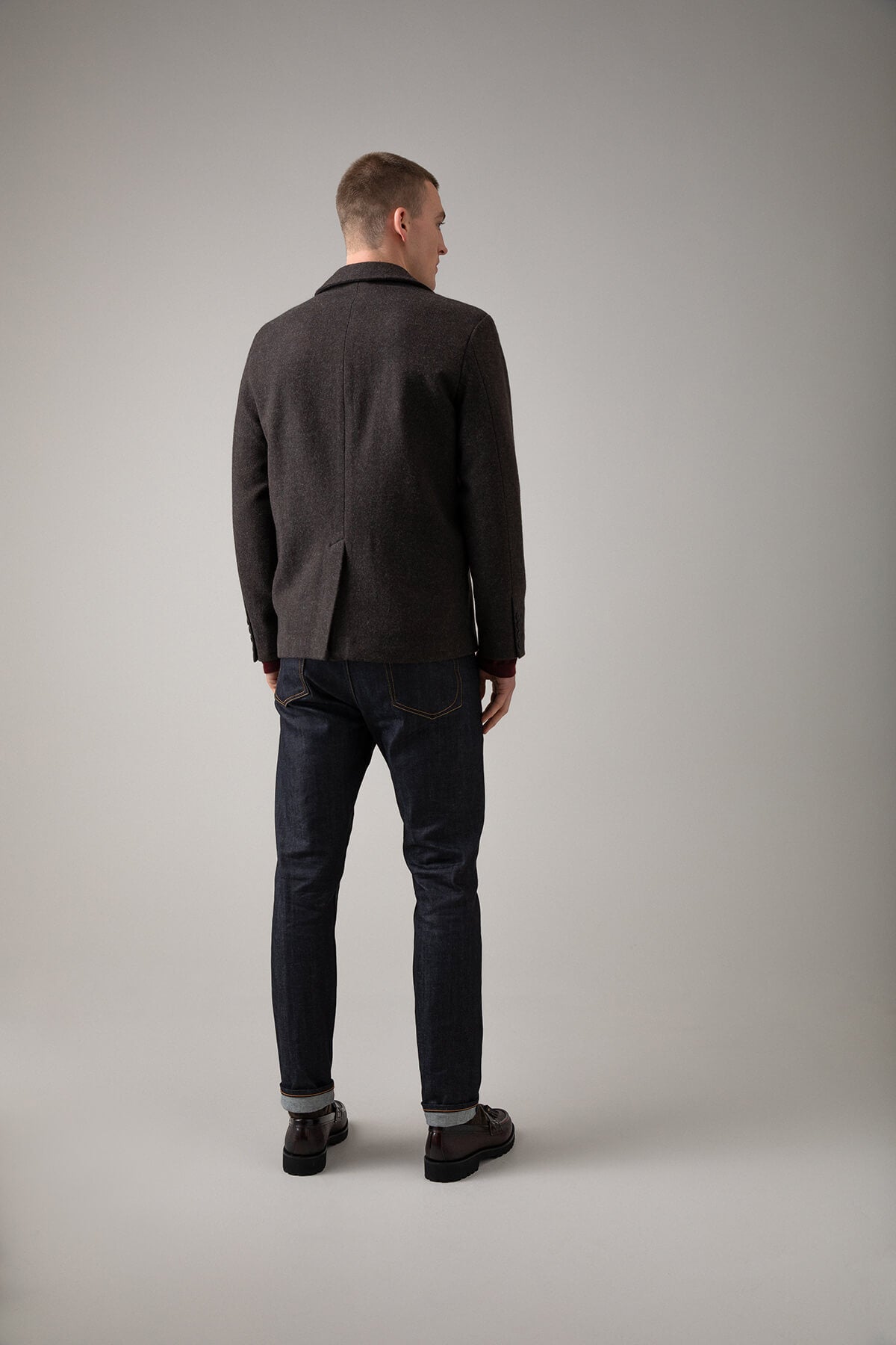 Johnstons of Elgin’s Men's Double Face Cashmere Jacket in Mid grey on model wearing blue jeans and red jumper on a grey background TA000517RU7292