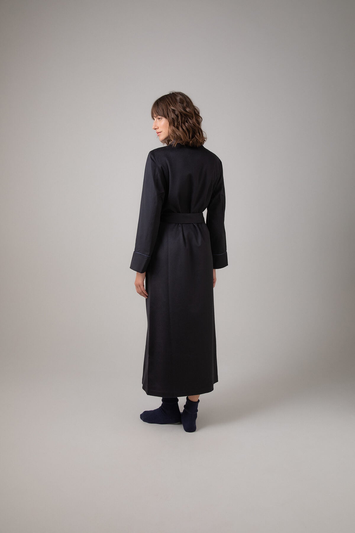 Back of Johnstons of Elgin Women's Cashmere Dressing Gown with Silk Lining in Navy worn with Navy Cashmere Socks on a grey background TA000473RU65880