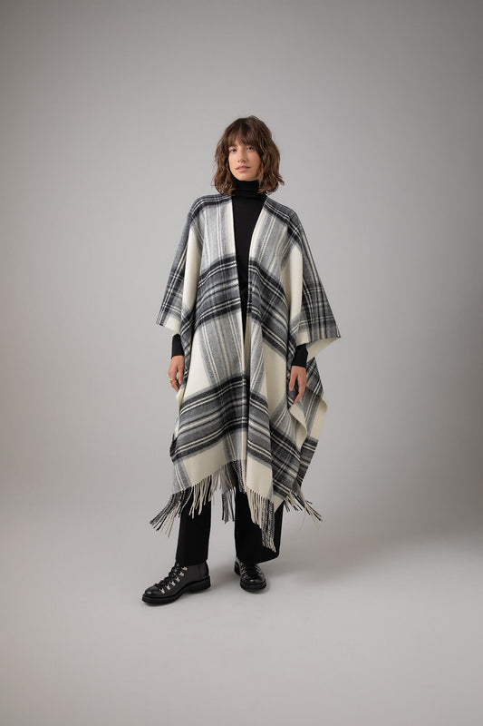 Johnstons of Elgin Stewart Check Long Cashmere Fringe Cape worn with Black Roll Neck and Trousers on a grey background TA000500RU7275ONE