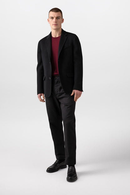 Johnstons of Elgin’s Men's Double Face Cashmere Jacket in Black on model wearing black trousers and red jumper on a white background TA000517RU6432